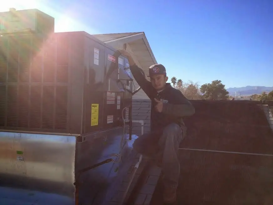 HVAC technician performing Boiler Repair on a rooftop unit in Troy
